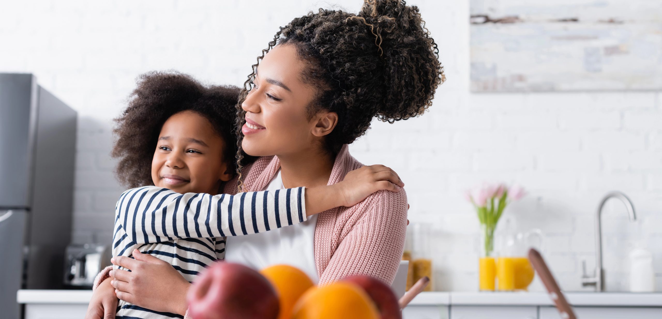 mom and daughter hugging, looking off screen